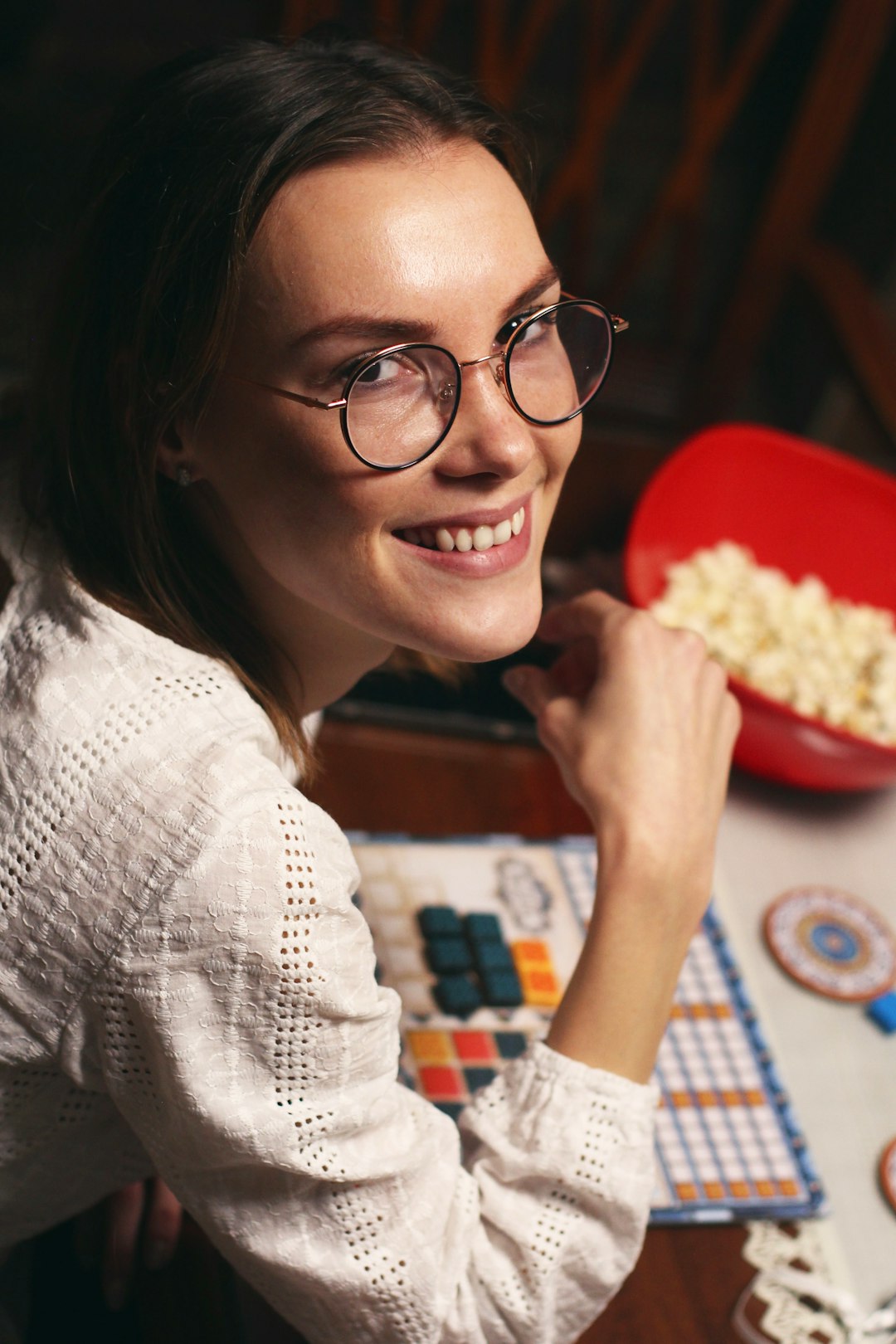 a-woman-sitting-at-a-table-with-a-bowl-of-popcorn-1sqtrgxbrjk
